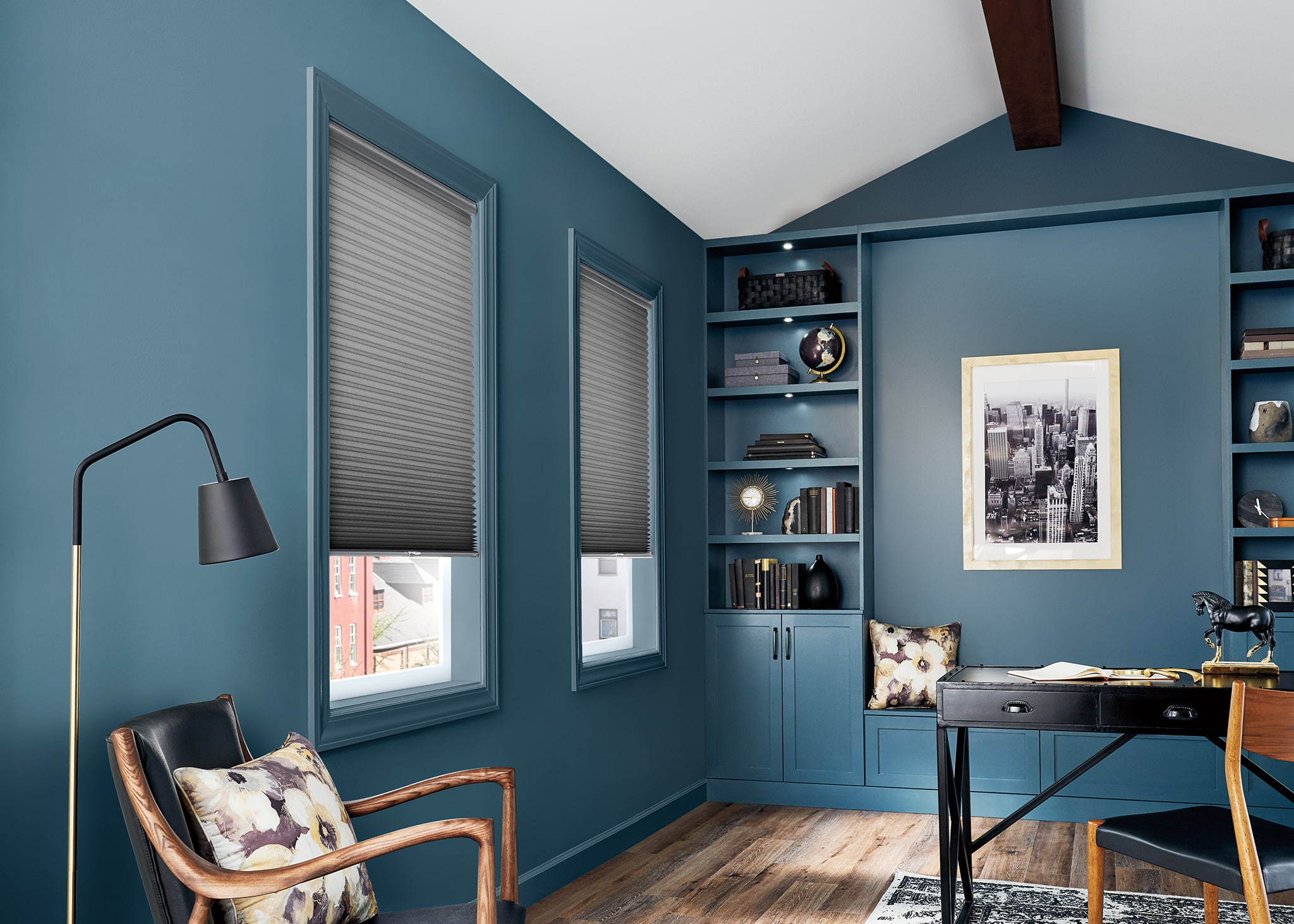 Cellular shades filtering in light to a blue office room.