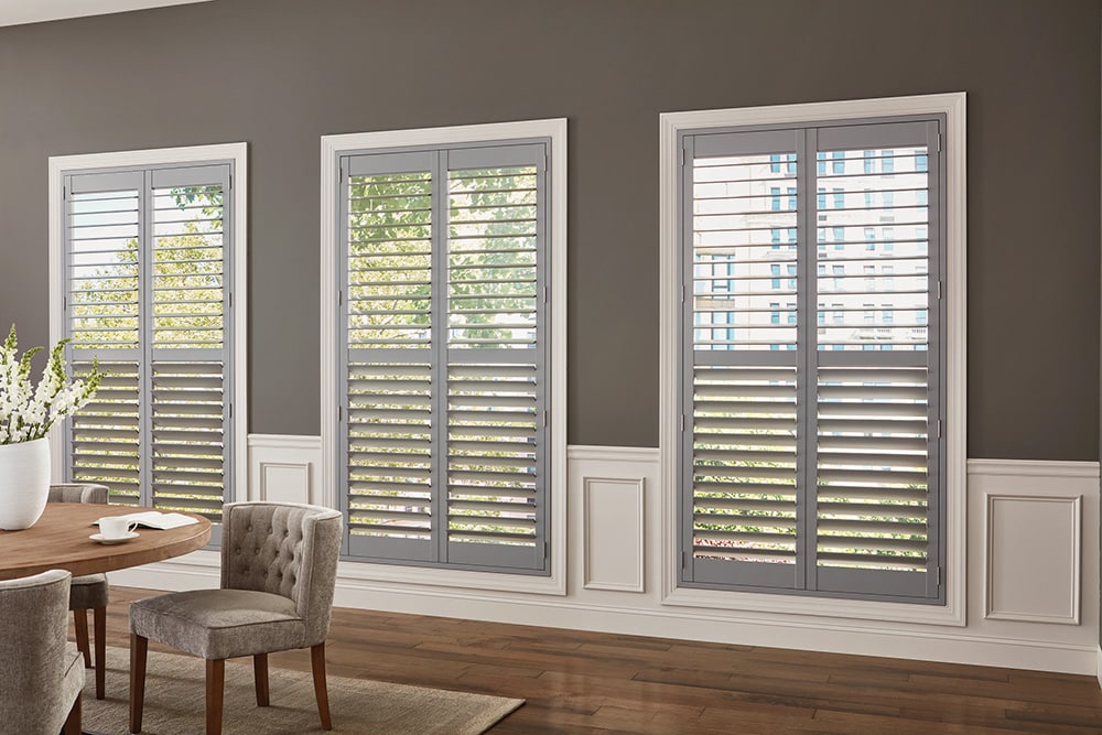 Plantation shutters for large interior windows in a gray and white dining room.