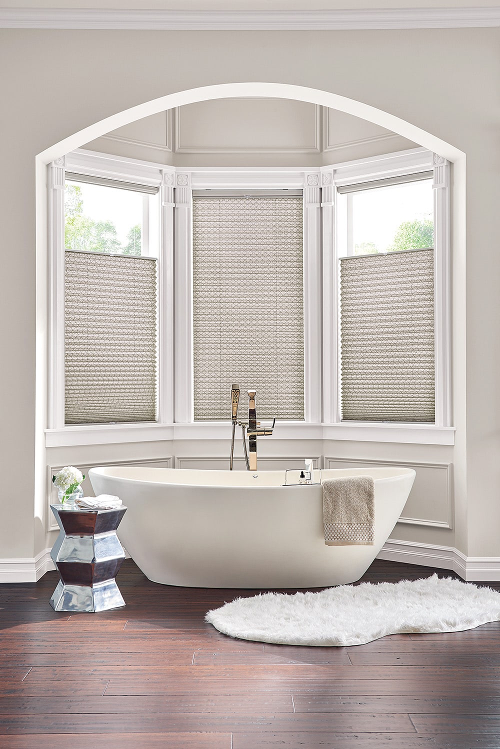 Pleated shades on bay windows surrounding a bath tub.