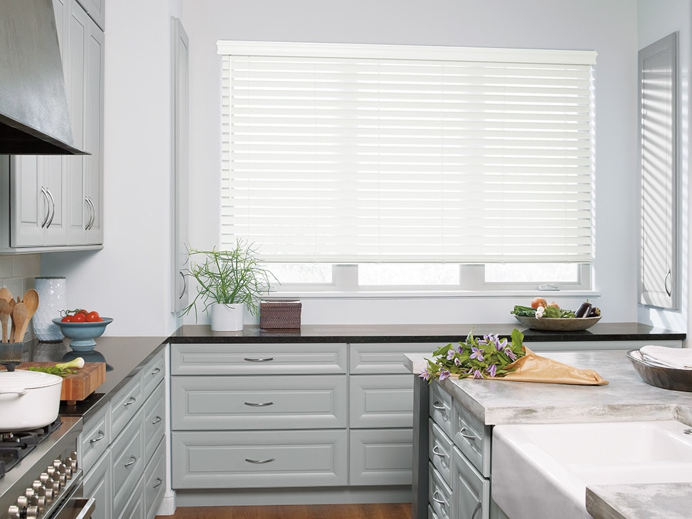A Custom made faux blind covering a large window, filtering in light into a sleek kitchen.