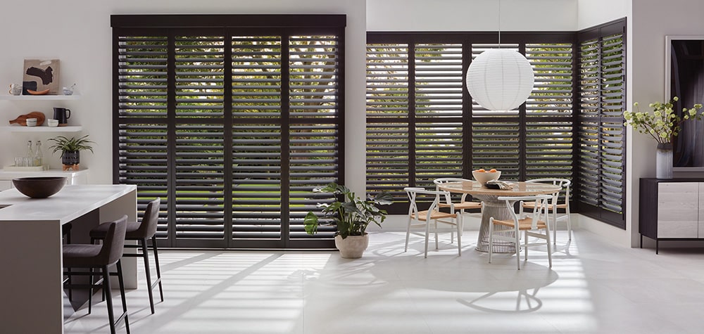 Ten faux wood shutters filtering in light into a stunning kitchen and dining room.